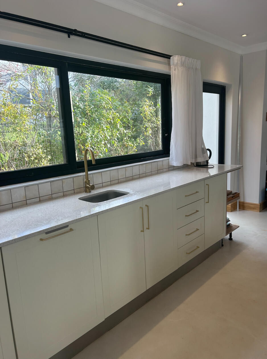 Kitchen A modern farmhouse style kitchen with a splash bowl and ample cupboard space. Shaker-style cupboards were sprayed in a hand-chosen off-white colour.